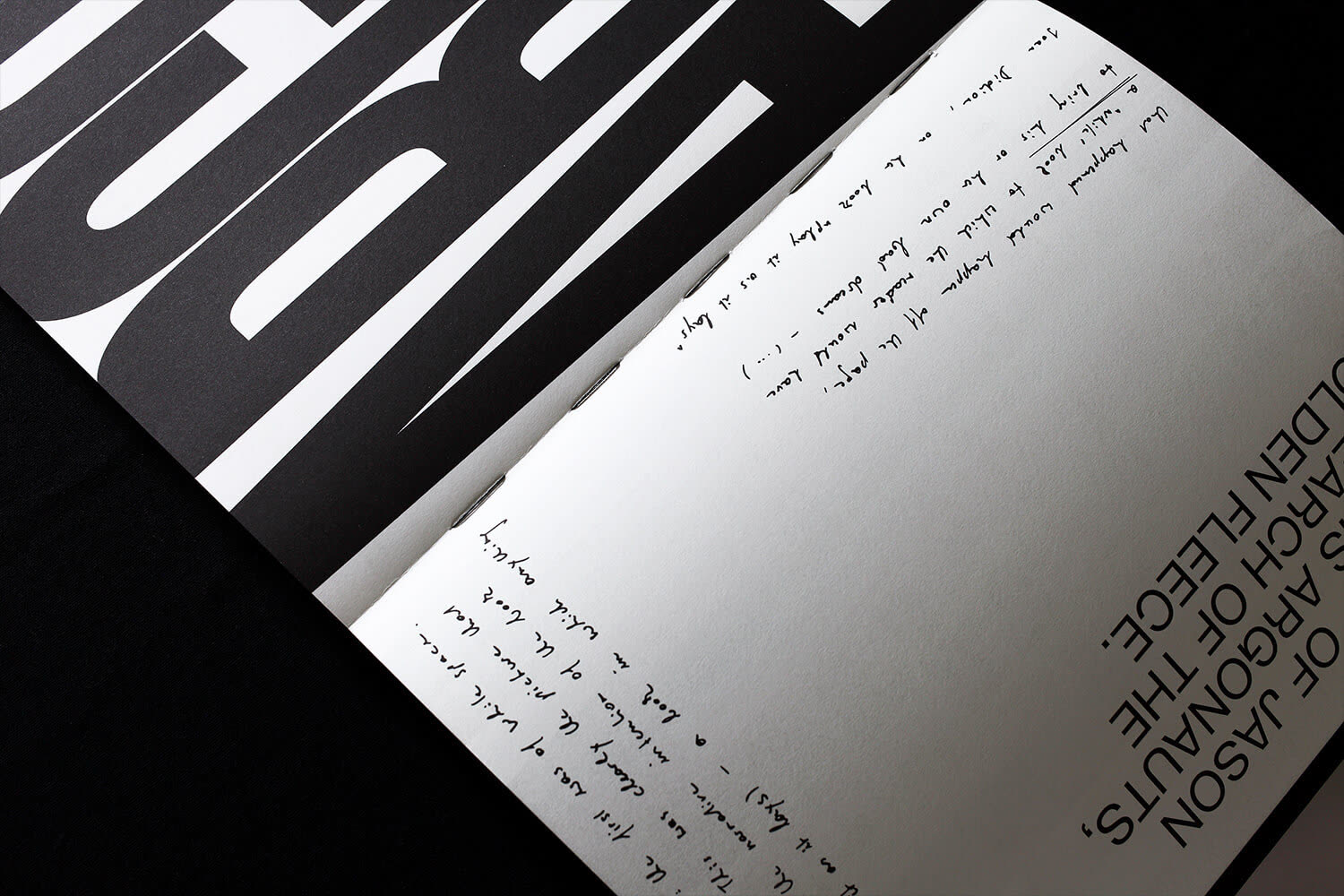 Handwritten text running across a spread beside the large title letters