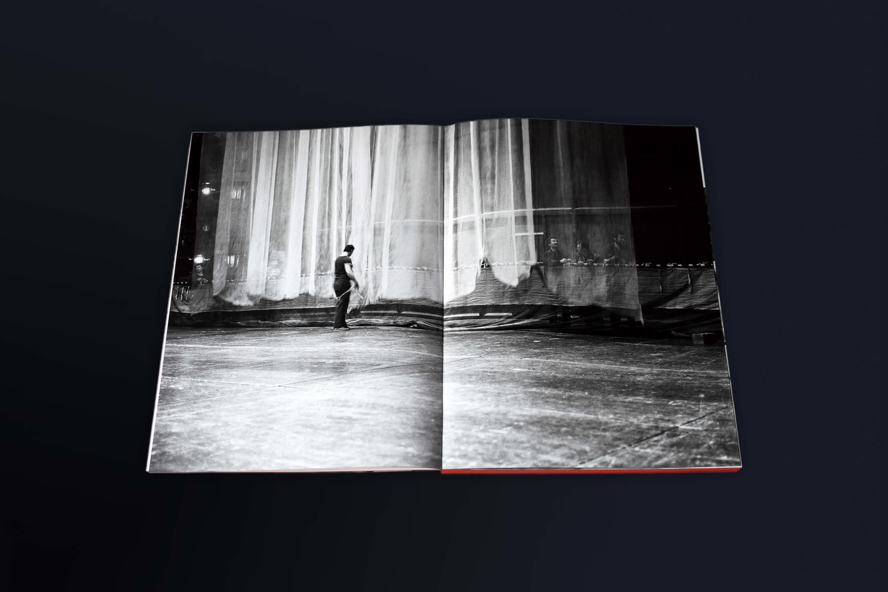 Spread with a figure in front of a large white curtain