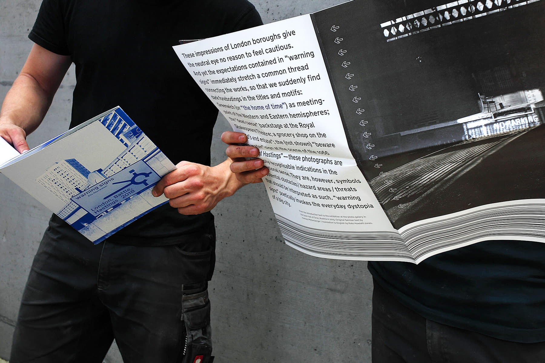 Someone reading the folded newspaper with the catalogue under one arm