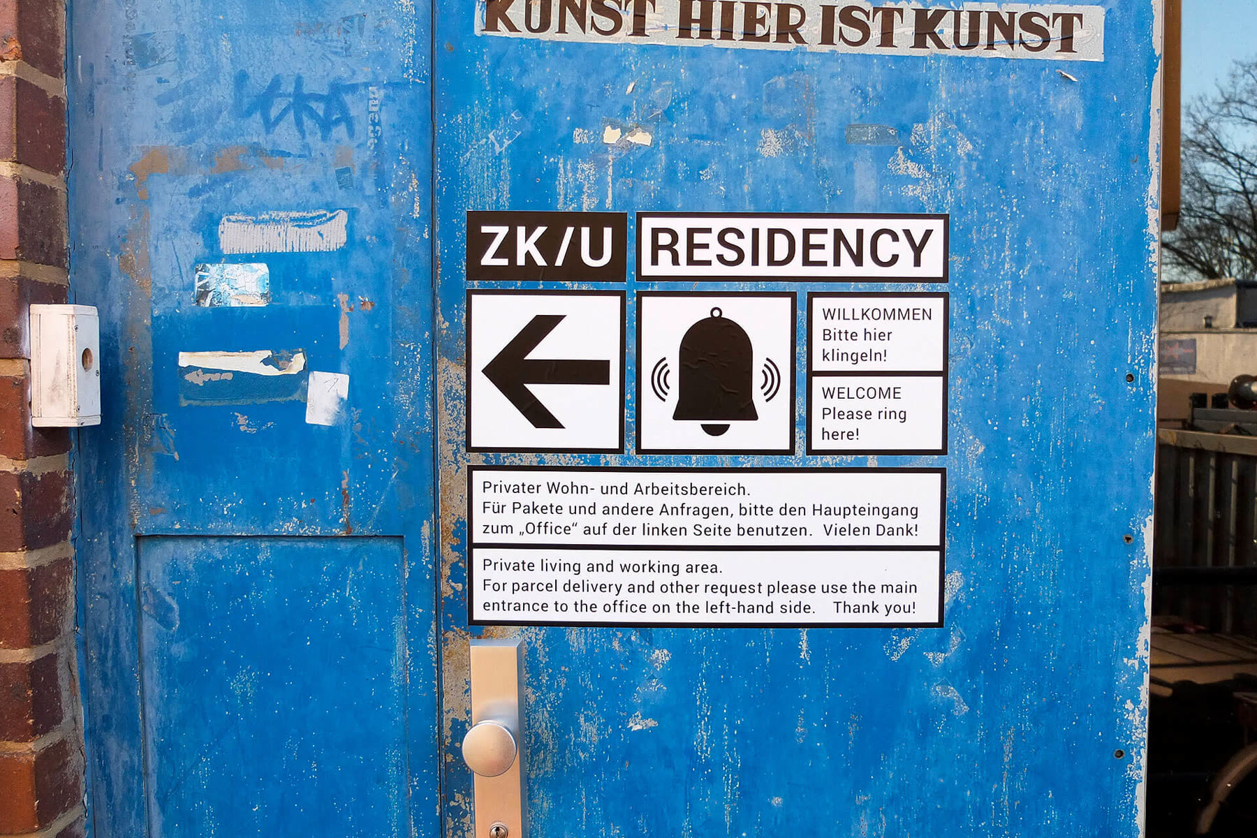 Sign with an arrow and a bell on a blue door