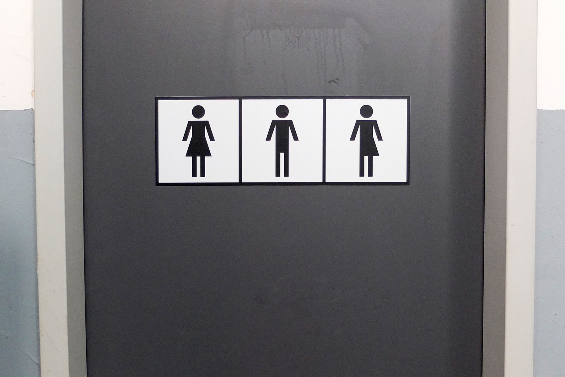 Three toilet pictograms on a grey door
